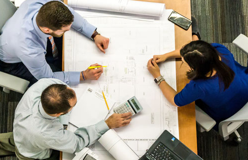 People sitting at a table discussing the advantages of the Design-Build Delivery System for Commercial Roofing.