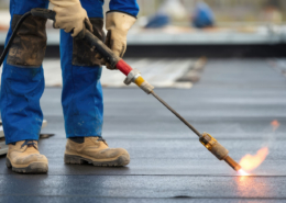 Flat roof flashing being repaired by a roofing contractor.