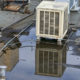 Flat commercial roof with a large puddle of ponding water around rooftop HVAC units.