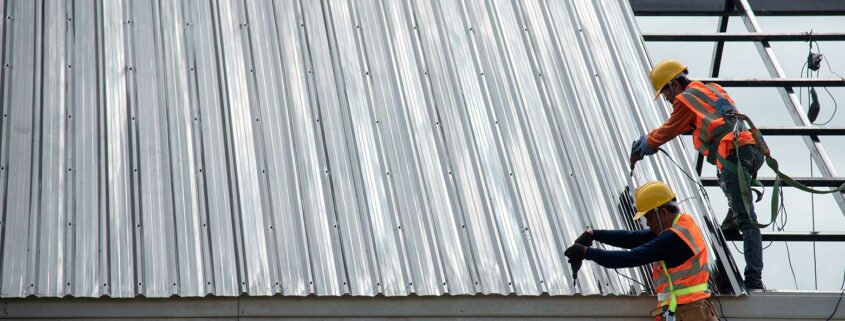 Roofers installing a metal roof on a commercial building.