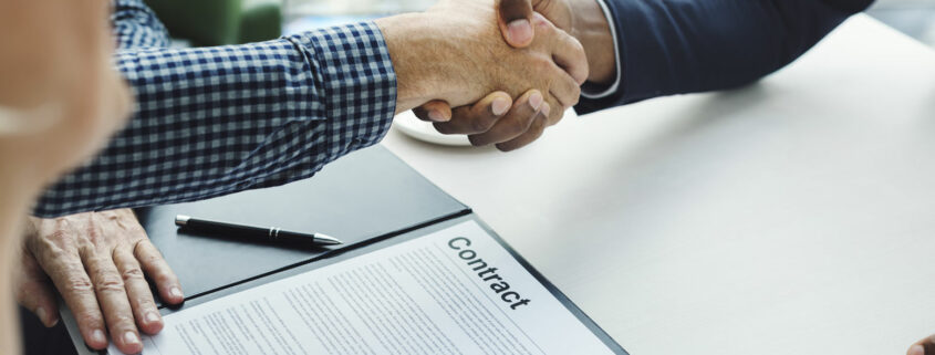 Individuals shaking hands over a contract.