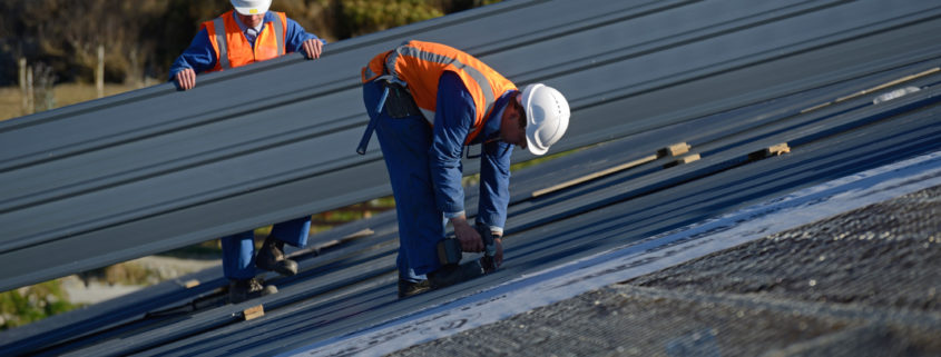 Two men conducting an industrial roof repair on a commercial building.